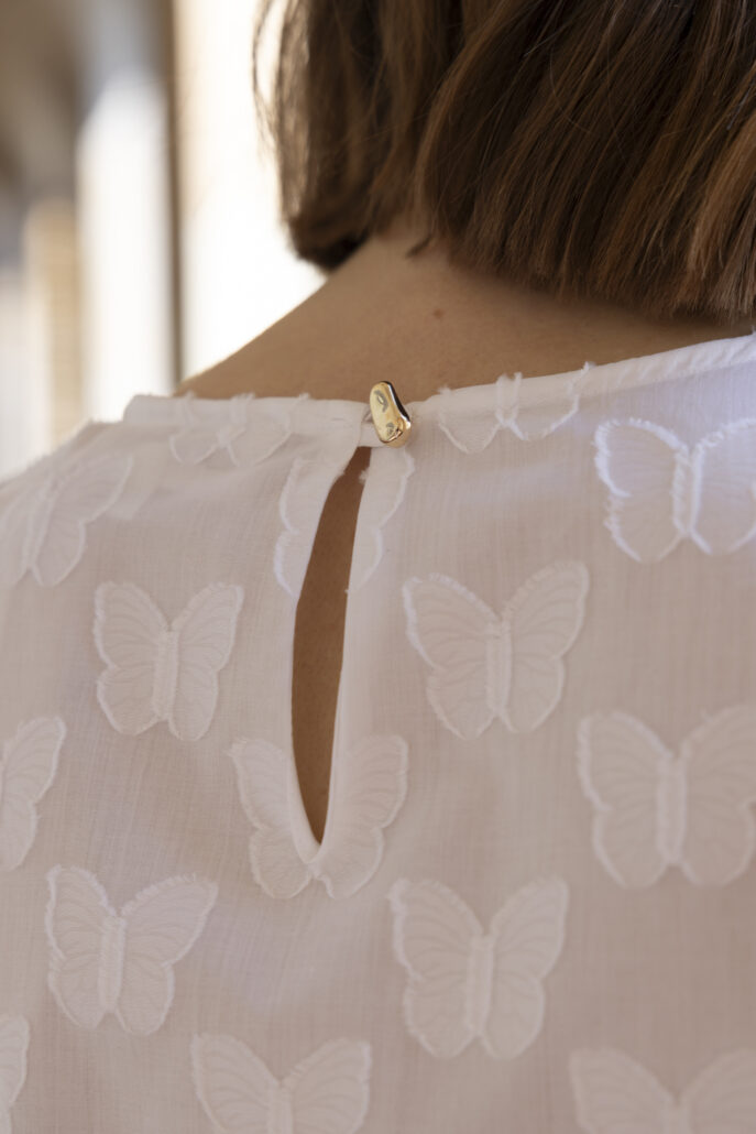 Cropped Bluse „Mia“ mit Butterfly „Coupe Back“ – auch als Abschneider oder Scherli bezeichnet – bei der der 3D-Effekt durch das Abschneiden der flottierenden Fäden des Jacquards entsteht. Von Liebe zum Detail zeugt ein goldener Zierknopf.